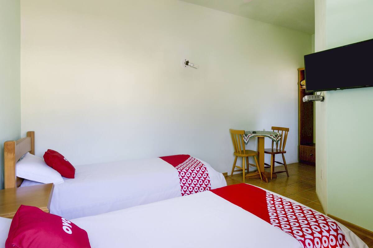 Ein Hotelzimmer mit zwei Betten, einem Schreibtisch, einem Stuhl und einem Fernseher.
