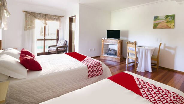 Habitación de hotel con dos camas, un escritorio, una silla, un televisor y un cuadro en la pared.