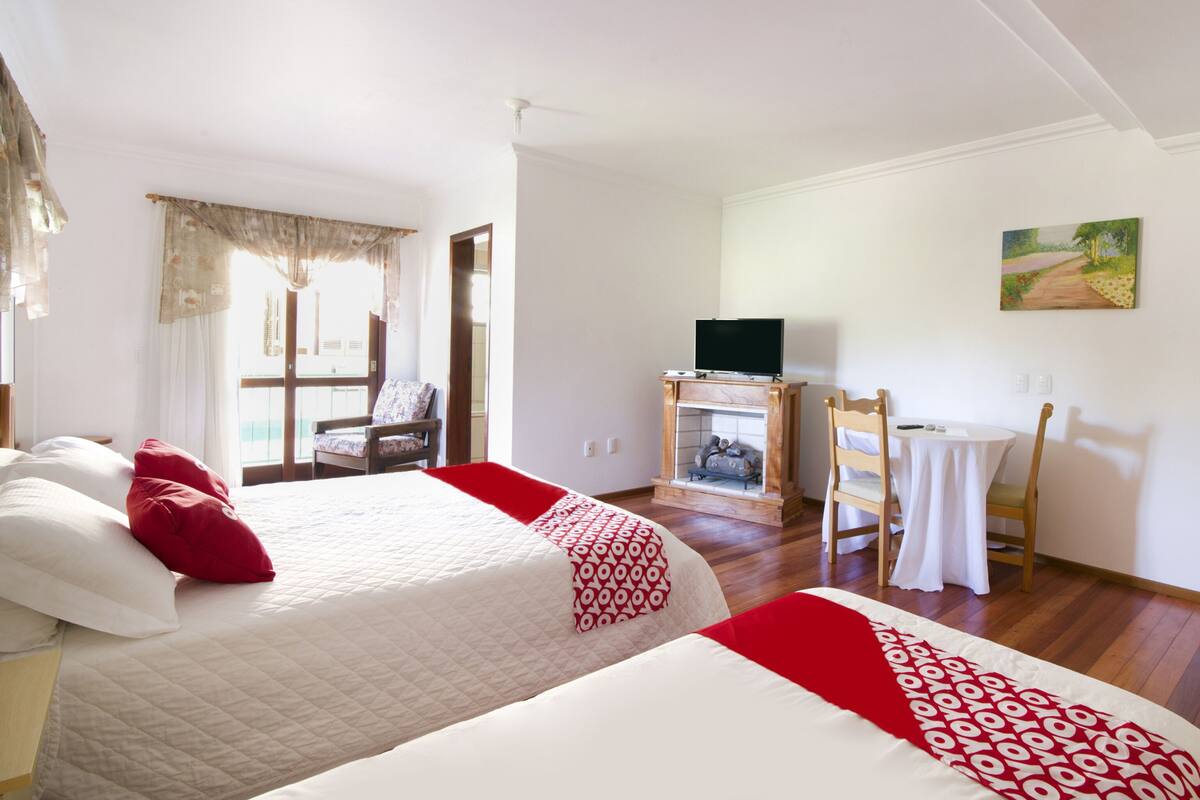 Ein Hotelzimmer mit zwei Betten, einem Schreibtisch, einem Sessel, einem Fernseher und einem Bild an der Wand.