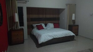 A bedroom with a bed, two nightstands, a wooden headboard, and a red accent pillow.