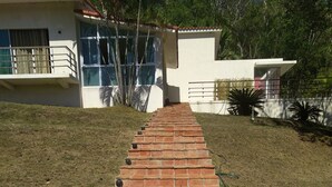 A pathway leading to a building with a modern design, featuring a series of steps and a visible water hose.