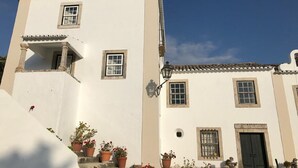 Un edificio de dos pisos con fachada blanca, varias ventanas y una puerta negra.