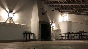 Un salón amplio con techo alto, un arco de piedra y una larga mesa con sillas.