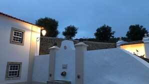 Un edificio blanco con un muro de piedra, una ventana pequeña y un accesorio de iluminación.