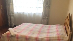 A bed with a plaid bedspread, a wooden headboard, and a small round table with a woven base. - letting 2 bm fully furnished apartment  along  Waiyaki way  westland Raphta road (westlands)