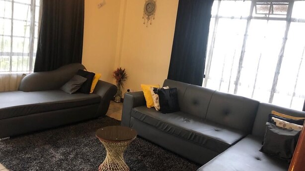 A living room with two sofas, a coffee table, and a decorative wall clock. - letting 2 bm fully furnished apartment  along  Waiyaki way  westland Raphta road (westlands)