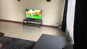 A living room with a television on a stand, a sofa, and a rug. - letting 2 bm fully furnished apartment  along  Waiyaki way  westland Raphta road (westlands)