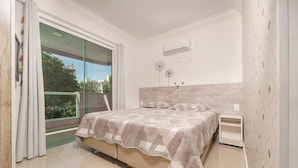 Une chambre avec un lit, une table de chevet, un climatiseur fixé au mur et une vue sur la verdure.