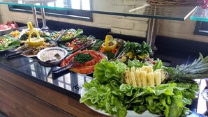 Un bufé con diversos alimentos, como ensaladas, frutas y una variedad de platos.