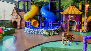 Zona de juegos infantiles con toboganes, estructuras para escalar y un foso de pelotas.