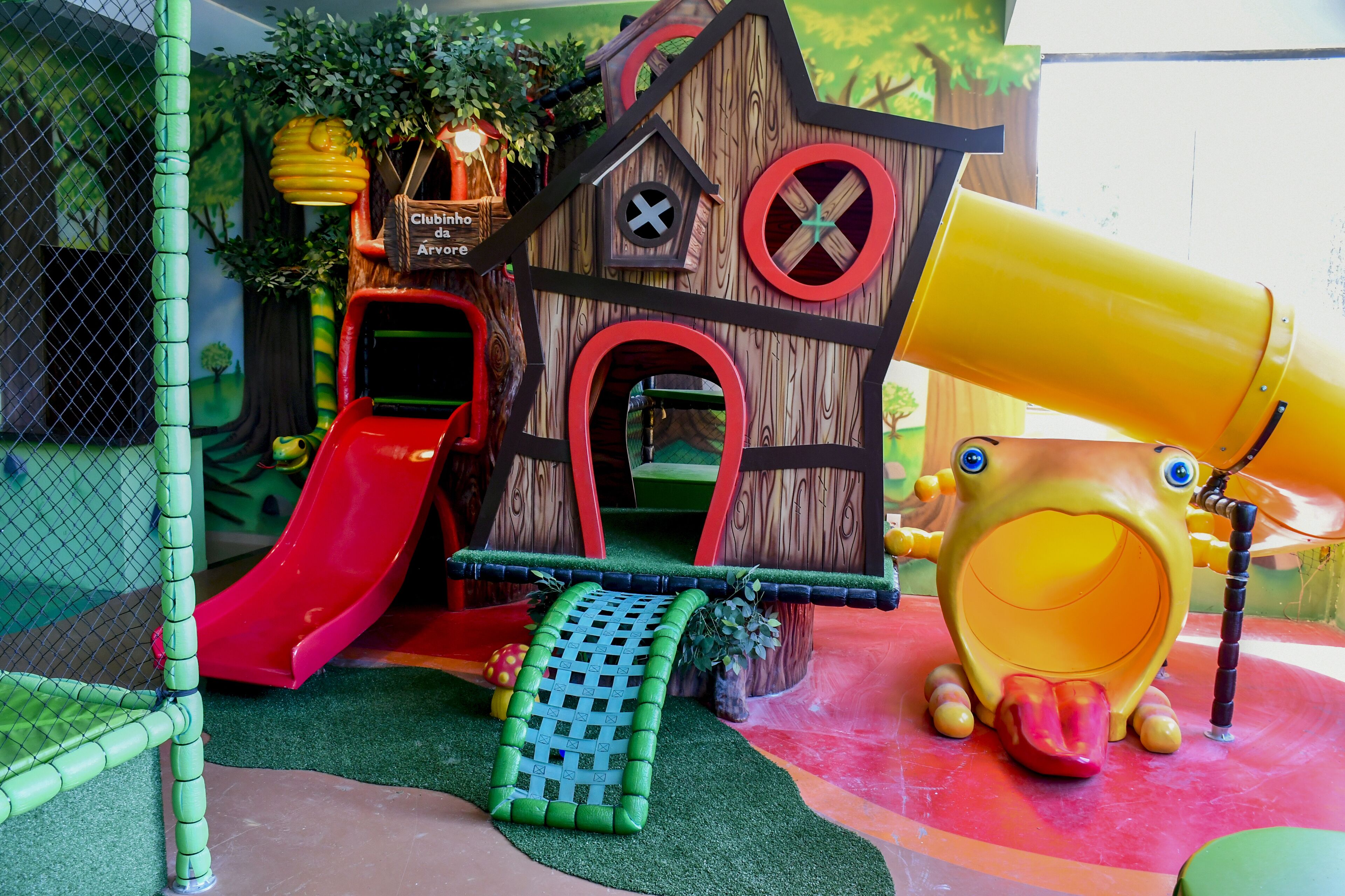 A children's play area with a slide, climbing net, and a playhouse.