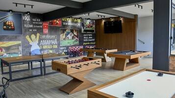 A room with three foosball tables, a pool table, and a billiards table.