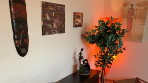 Un mueble de madera con una cesta tejida, una planta en maceta y una obra de arte en la pared.