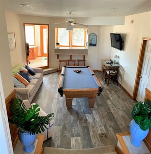 Amplia sala de estar con mesa de billar, sofá y televisor.