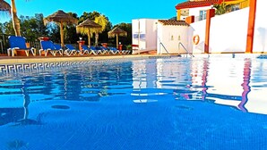 Ein Schwimmbecken mit klarem, blauem Wasser, Liegestühlen und einem Gebäude mit einem Rettungsring.