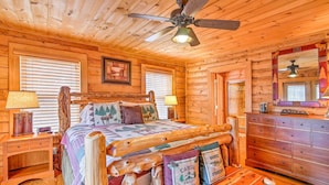 Un dormitorio tipo cabaña de madera con cama, cómoda y ventilador de techo.