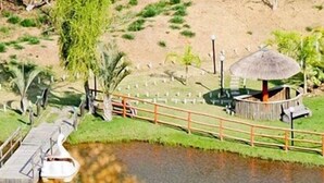 A bridge over a water body, a wooden fence, and a thatched-roof structure.
