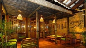 A rustic interior with wooden furniture, hanging lamps, and stone walls.