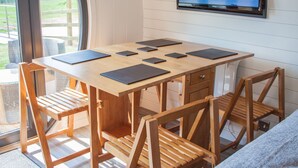 Een houten tafel met zes zwarte tabletstandaards, een houten stoel met rugleuning en een aan de muur bevestigde televisie.