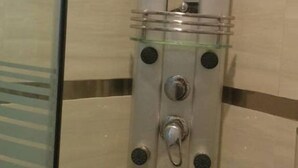 Une cabine de douche dotée d’un panneau de commande et d’un miroir.