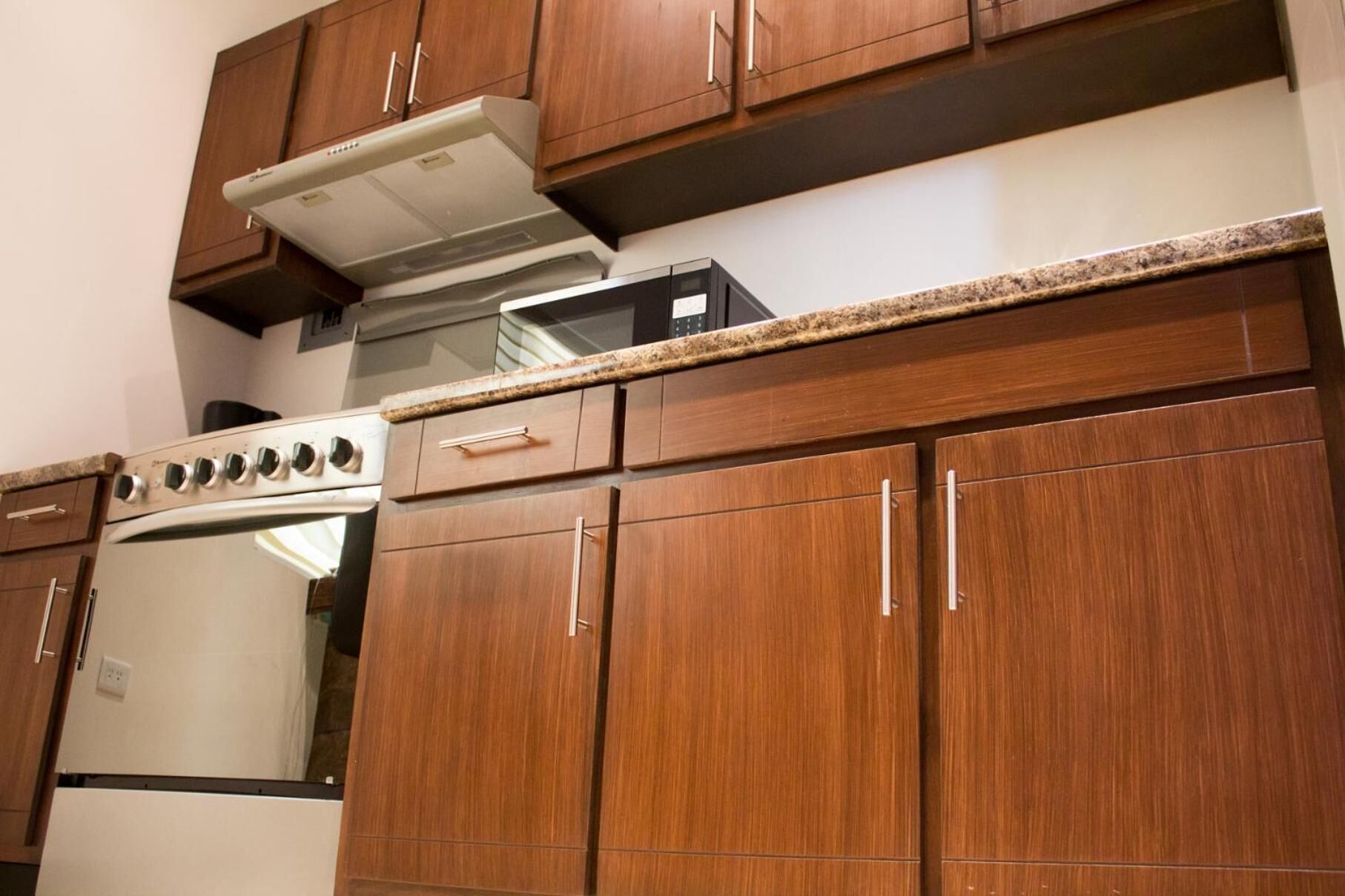 Una cucina con mobili in legno, una cappa in acciaio inossidabile, un forno a microonde e un piano cottura.