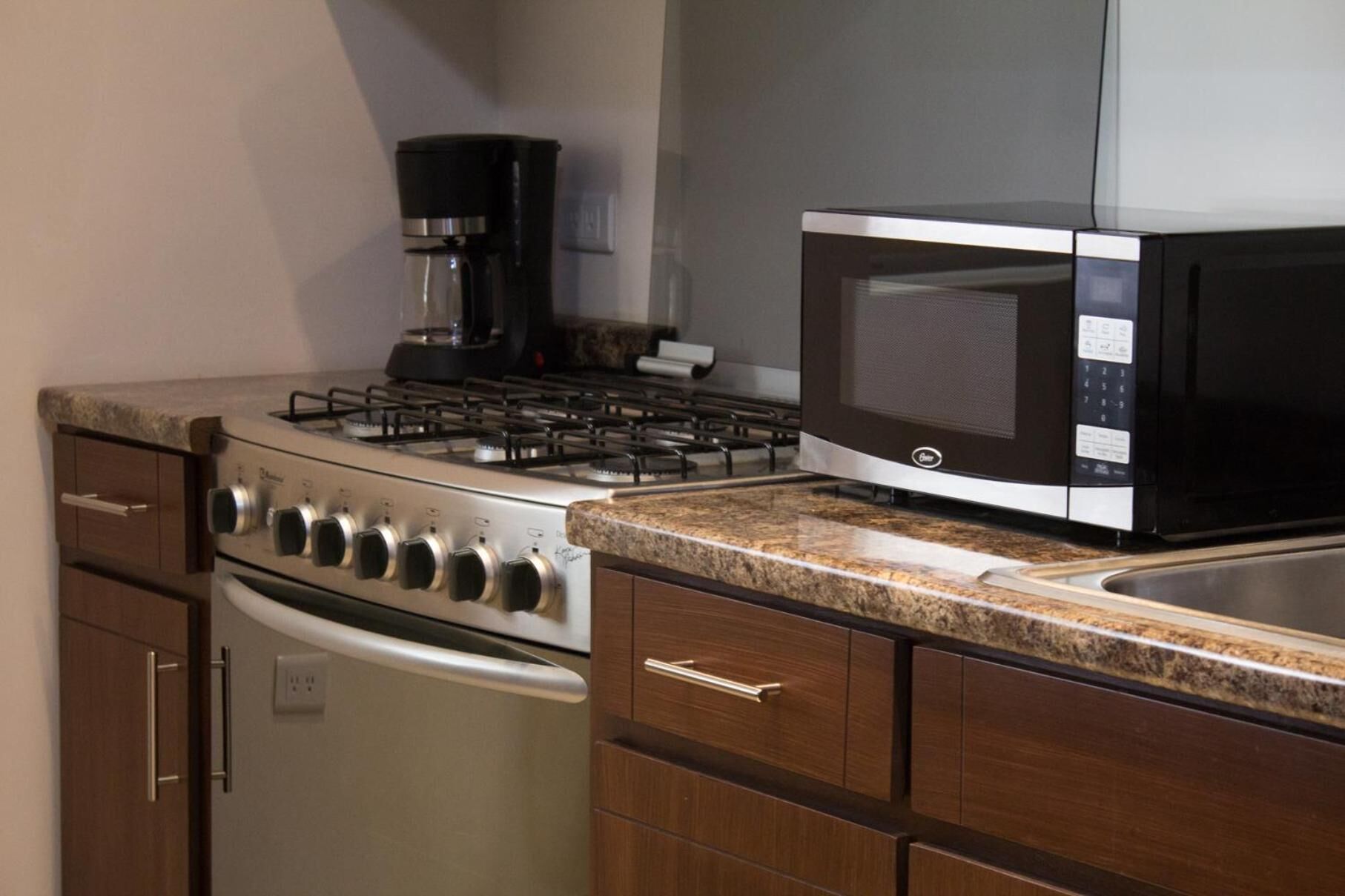 A kitchen with a gas stove, a coffee maker, a microwave, and stainless steel appliances.