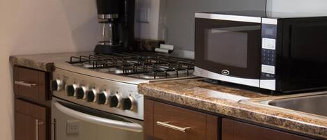 A kitchen with a gas stove, a coffee maker, a microwave, and stainless steel appliances.