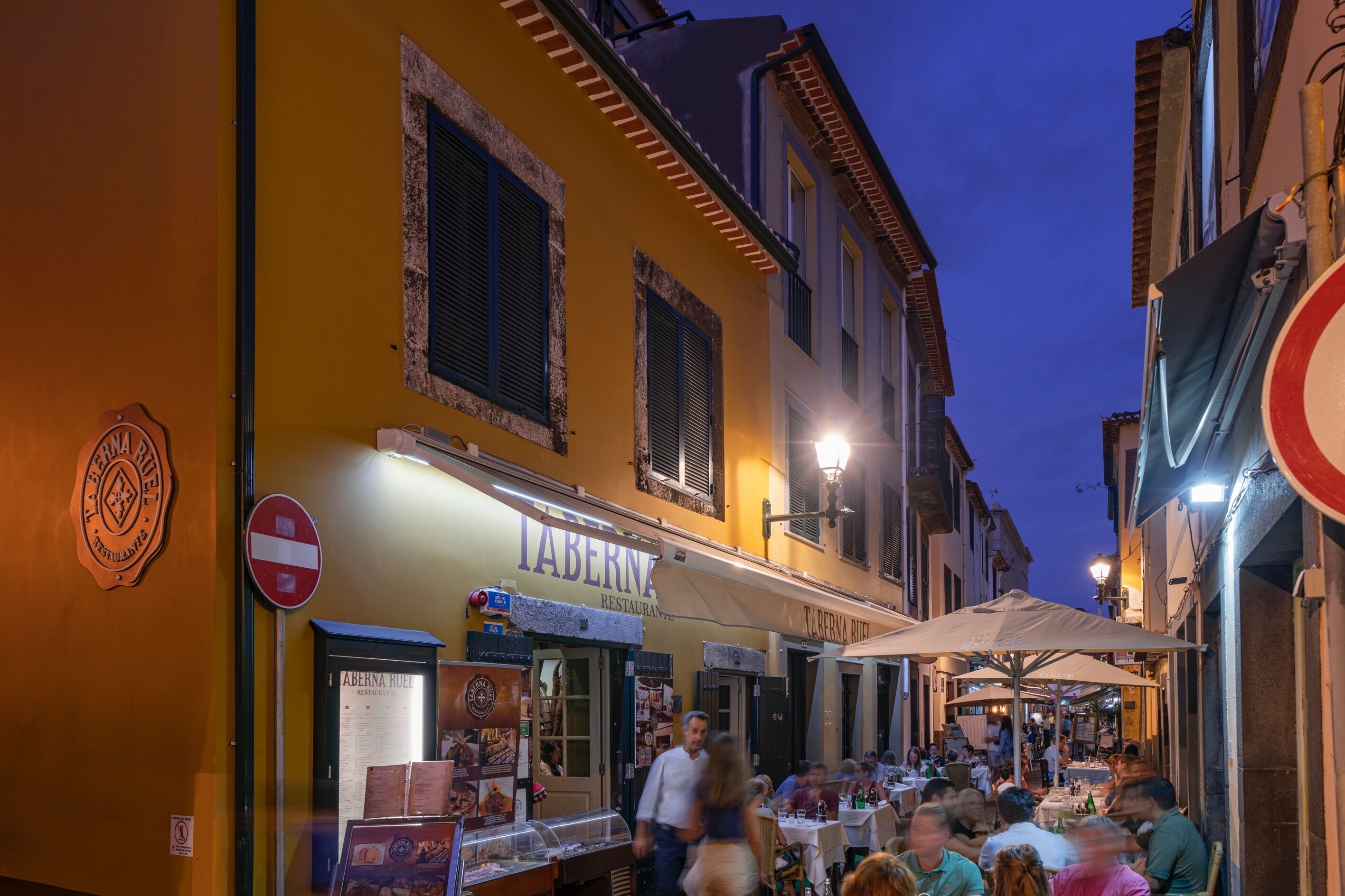 A street with outdoor seating at a restaurant named "Taberna".