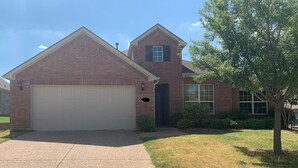 A two-story brick house with a garage, a small porch, and a tree in the front yard. - Lovely house with Sky light, Sun Room. (Mc Kinney)