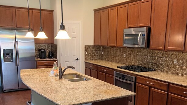 A kitchen with wooden cabinets, granite countertops, stainless steel appliances, and pendant lighting. - Lovely house with Sky light, Sun Room. (Mc Kinney)