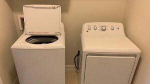 A laundry room with two white front-loading washing machines and a dryer. - Lovely house with Sky light, Sun Room. (Mc Kinney)