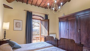 Een slaapkamer met een groot bed, een garderobe, een kroonluchter en een raam met gordijnen.
