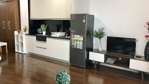 A modern kitchen with white cabinets, a stainless steel refrigerator, and a dining area with a white table and chairs.