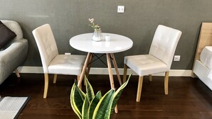 A room with two white leather chairs around a small white table, a potted plant, and a grey textured wall with electrical outlets.