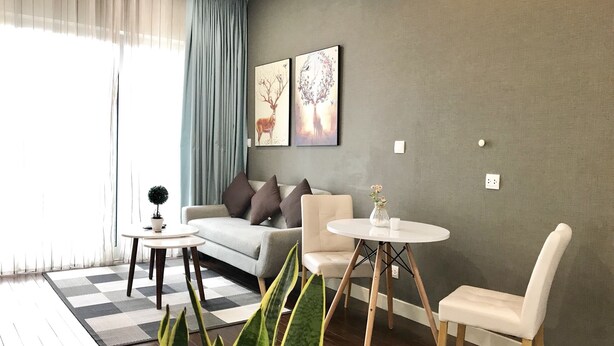 A modern living room with a sofa, two chairs, a coffee table, and a large plant.