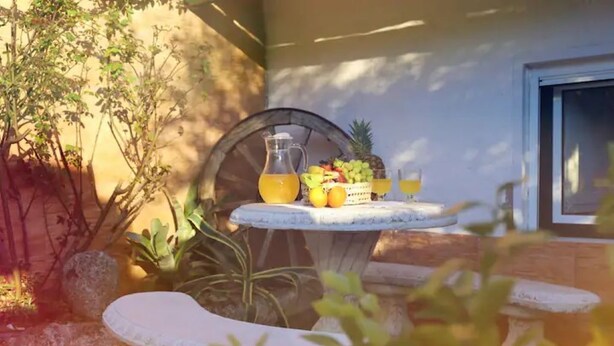 An outdoor seating area with a table set for two, featuring a pitcher of orange juice, a fruit basket, and a glass of orange juice. - Refúgio Saloio in Lousa-LRS (Lousa)