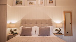 A neatly made bed with a headboard, two bedside lamps, and a framed mirror on the wall. - Rosedale Cottage | sleeps 4 - Hot Tub, Dog Friendly - 5* Gold Award (Pickering)