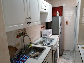 Een koelkast, een magnetron, kookgerei, borden en bestek, keukenrol