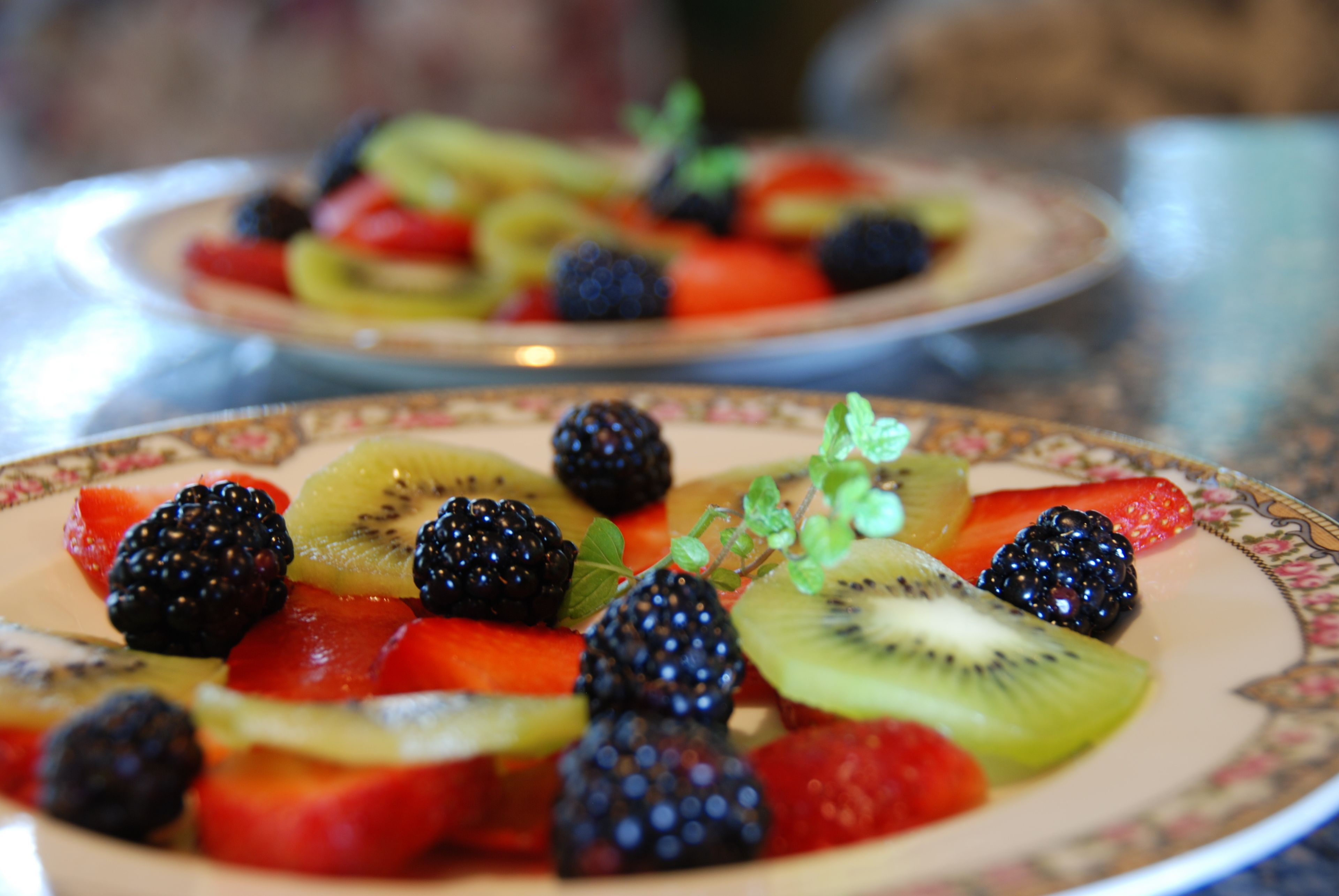 Un plato de fruta variada que incluye fresas, zarzamoras y rodajas de kiwi.