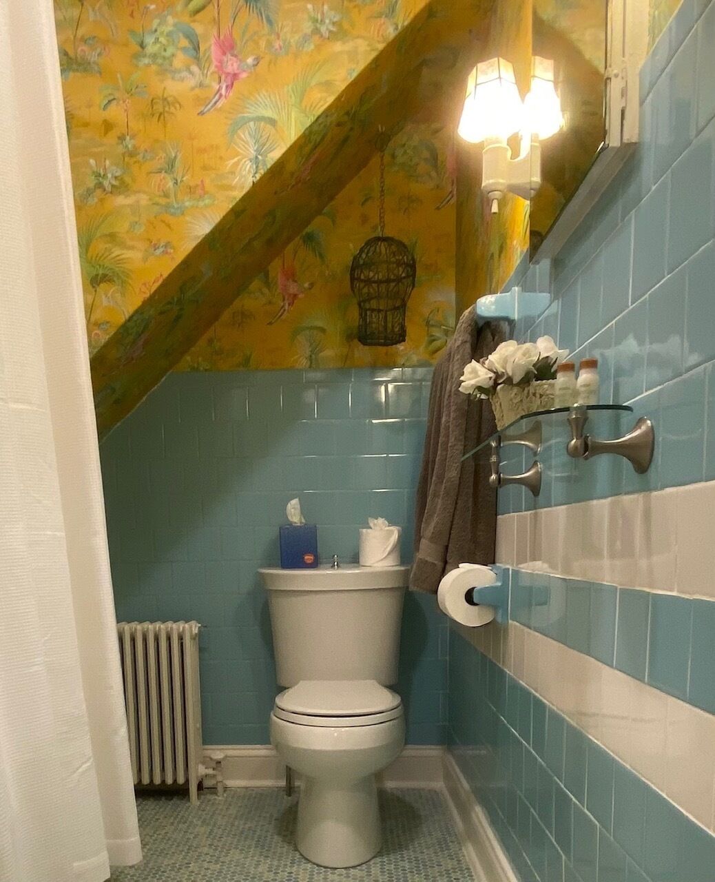 Ein Badezimmer mit Toilette, blauen Fliesen, einem Handtuchhalter und einer Zierteinrichtung an der Decke.