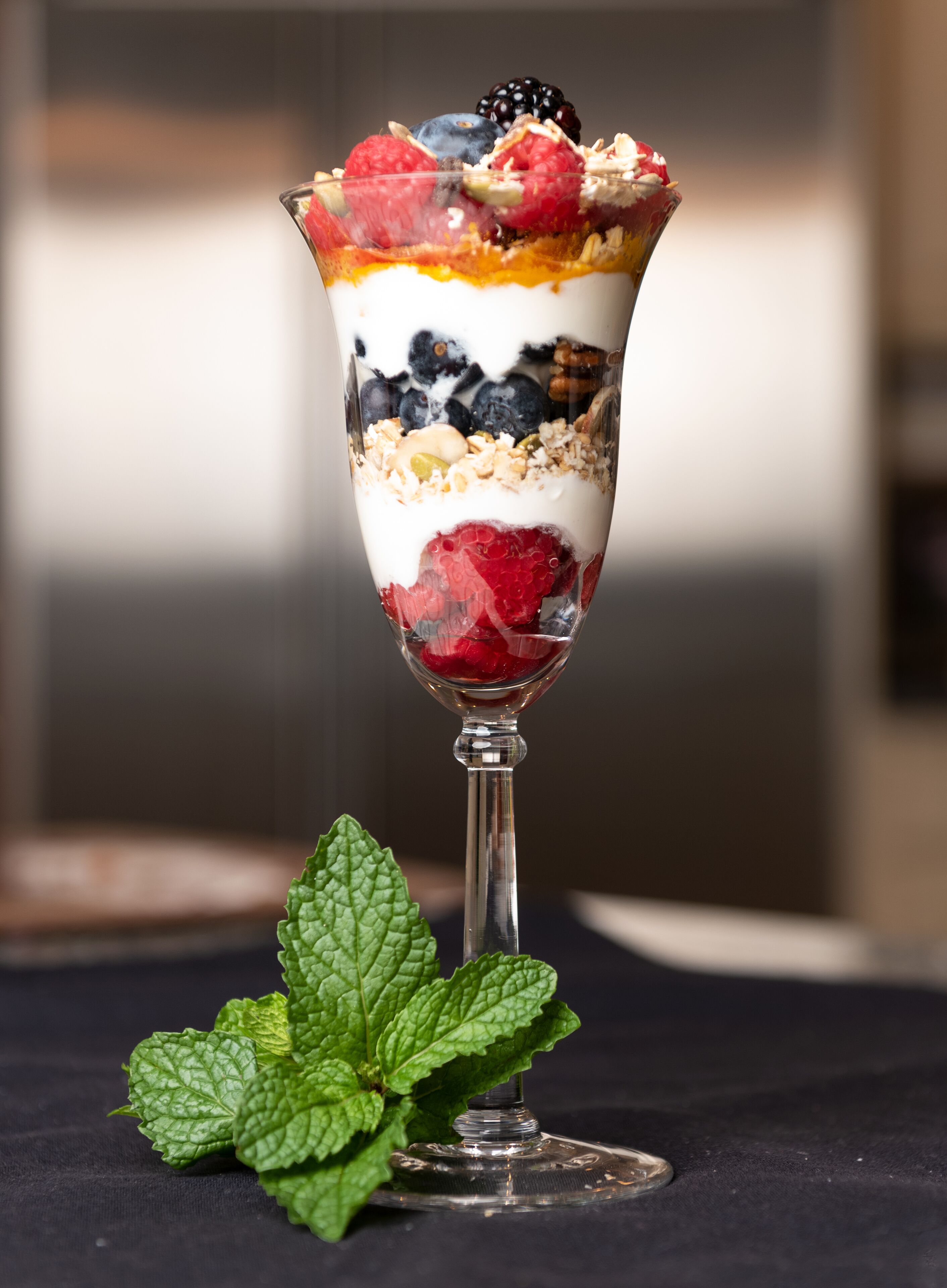 Ein Dessert im Glas mit Schichten aus Joghurt, Beeren und Granola.