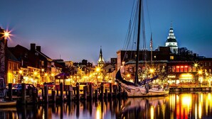 A waterfront town at dusk with a prominent church steeple and a large dome building. - Inn at Horn Point (Annapolis)