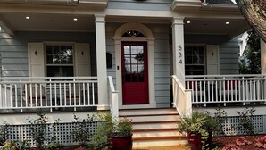 A two-story Inn Horn Point with a red door, white railings, and a stone pathway leading to the entrance. - Inn at Horn Point (Annapolis)