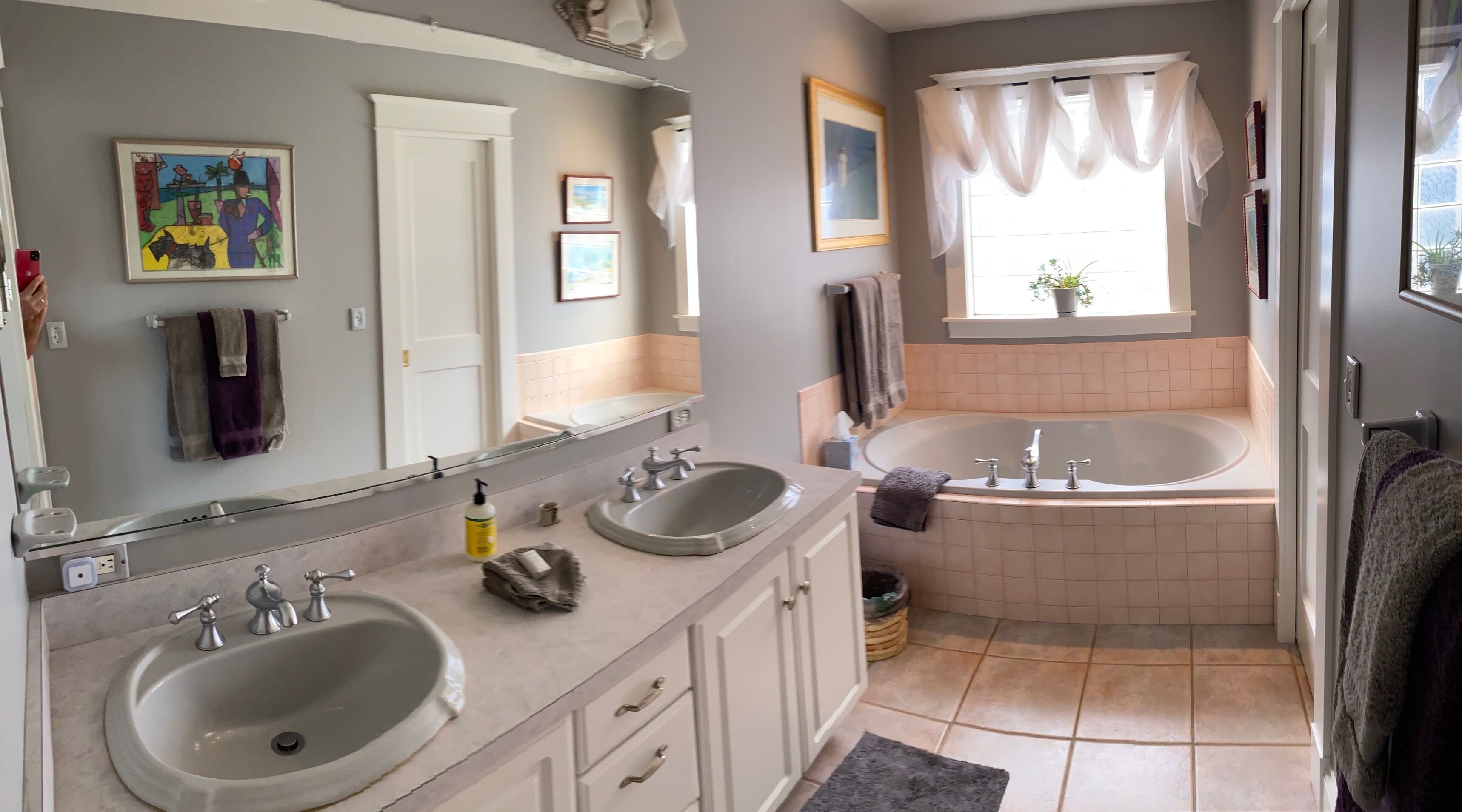 A bathroom with two sinks, a bathtub, and a large mirror.