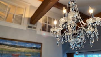 A chandelier with multiple arms and crystal decorations in a room with wooden beams and a painting on the wall.
