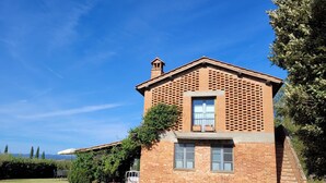 Un bâtiment en briques avec un petit balcon, une fenêtre et une porte.