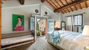 Une chambre à coucher avec un lit, un banc, un tableau et une vue sur l’extérieur.