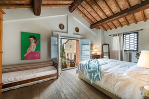 Un dormitorio con cama, un banco, un cuadro y vistas al exterior.