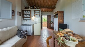 Une cuisine chaleureuse avec un plafond en bois, un réfrigérateur blanc et une table à manger où l’on peut voir de la nourriture.
