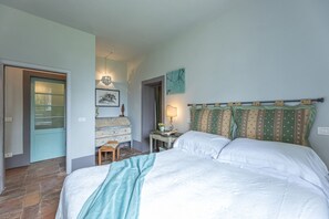 A bedroom with a bed, a nightstand, a dresser, and a door.